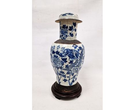 19th century Chinese blue and white crackle glazed baluster vase and cover, on hardwood stand, painted with a dragon amongst 