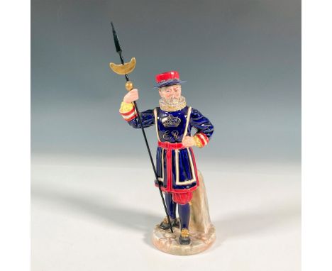 A figure of a Beefeater holding a halberd. Icon of a crown and ER in gold on the guard's front attire. Blue, red, white, gold
