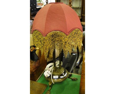 A brass triple column table lamp on 3 paw feet, with shade.