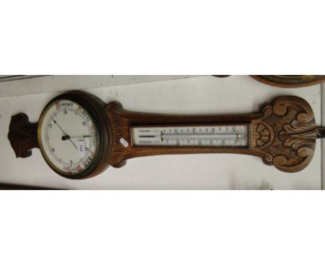 A carved oak wall barometer with thermometer.