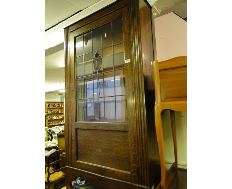 An oak single door bookcase with a coloured lead light glazed door.