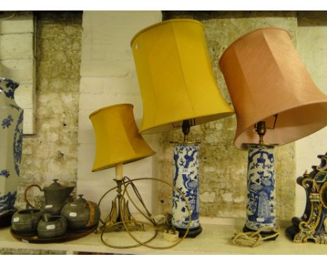 A pair of Oriental blue and white table lamps with bird of paradise decoration, a brass table lamp supported by 3 swans and a