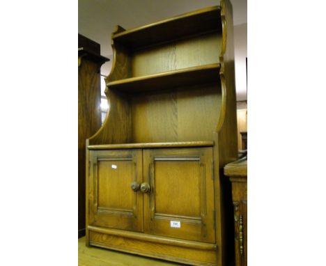 An Ercol elm waterfall open bookcase with cupboards to the base.