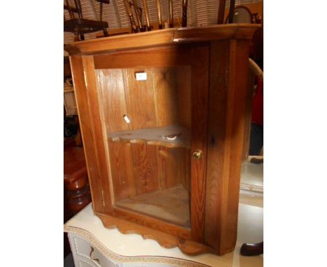 A Victorian stripped pine wall mounted corner cabinet with glazed door enclosing a single shaped shelf