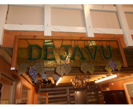 A vintage stained glass sign with vine and grape design, reading 'De Ja Vu'
