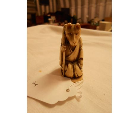 A 19th C carved ivory Chinese netsuke in the form of a seated bear with a robe and walking stick