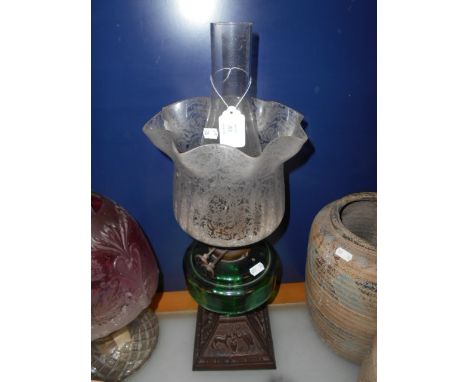 A Victorian oil lamp with floral decorated acid etched shade, green glass reservoir  with cast iron base moulded with fable s