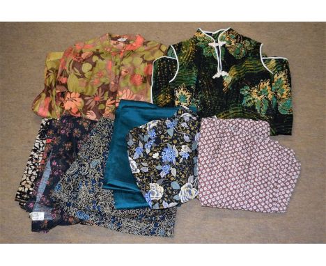 A quantity of batik and similar printed fabric ladies wear to include a black and green cheongsam, a printed satin shirt dres