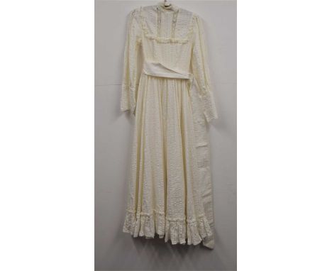 A c.1970's Laura Ashley dress, the full length cream cotton dress with high neck with lace trim, bib style front, with deep b