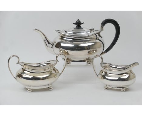 George V silver three piece tea service, maker H A, Sheffield 1923/25 and 1930, plain bombe form, the teapot with ebony handl