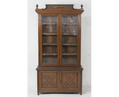 Continental oak bookcase cabinet, first half 20th Century, the top with reeded finials over two glazed doors opening to four 