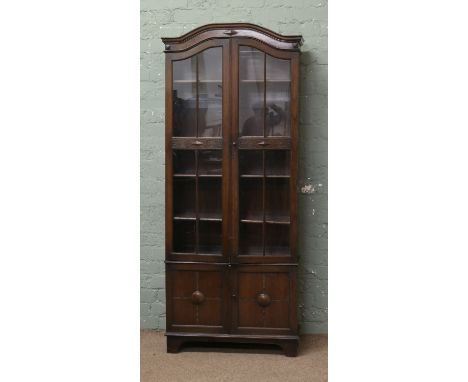 An astrigal glazed oak dome top bookcase raised on a cupboard base over bracket feet.