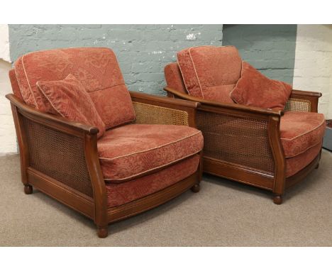 A pair of Ercol upholstered easy chairs with cane work sides.