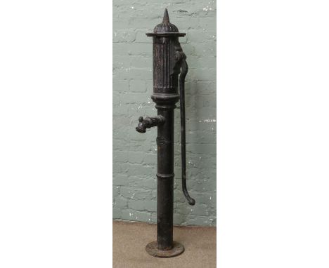 A vintage painted cast iron village water pump with decorative ribbed spout and ornate finial
