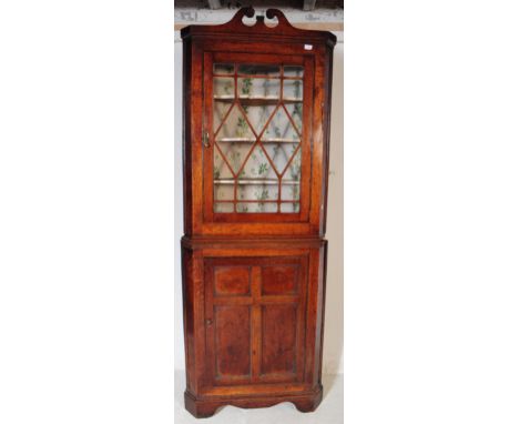 A George III oak wood glazed top corner cabinet. The cabinet raised on bracket feet with a shaped skirt to lower. Featuring a