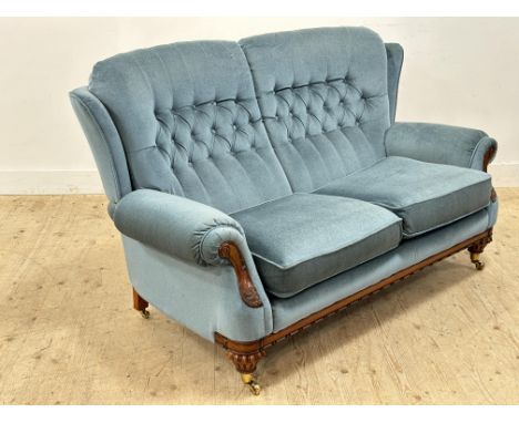 A walnut framed button back sofa with fluted supports, brass caps and castors (h.100cm x l.165cm x w.83cm)