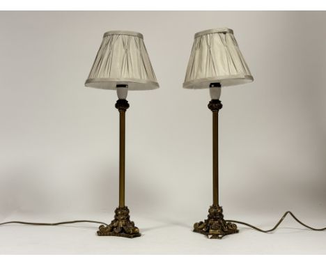 A pair of gold painted table lamps raised on three foliate scroll style feet, both with grey lampshades. (chip/loss to base) 