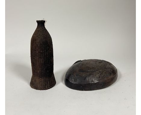 An oval hollowed and carved wood Borneo dish with stylized design carved verso (l. 33cm) together with a vintage cane work bo