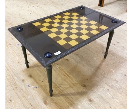 Retro side table with a rectangular smoked glass top decorated with a two tone chess board, standing on turned tapering suppo