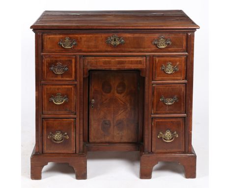 having a cross banded top above eight graduating drawers and a central cupboard to the kneehole, the drawer front having cros