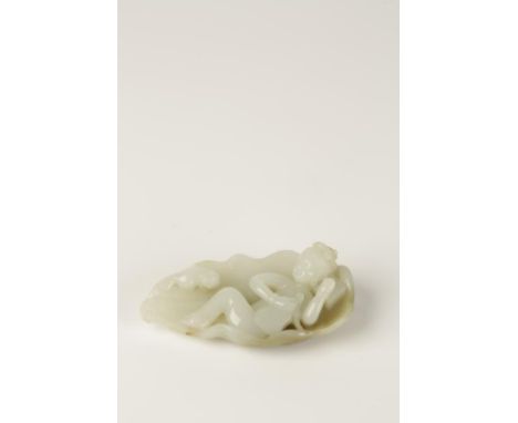 A CHINESE PALE CELADON JADE FIGURE of a woman holding a fan reclining on a large lotus leaf, a cat to one side, the back of t