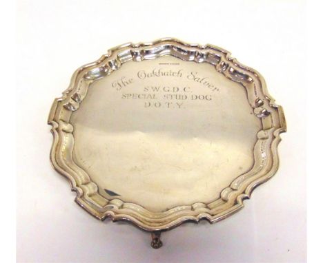 A SILVER SALVER Sheffield 1929, of circular shaped outline with a moulded rim, on three supports, inscribed to front and reve