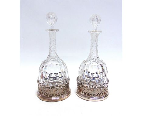 A PAIR OF CUT GLASS DECANTER AND STOPPERS  in Old Sheffield Plate coasters, 33cm high overall
