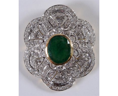 AN EMERALD AND DIAMOND PANEL BROOCH PENDANT  unmarked, the oval cut, approximately 10.5 by 8.2 by 5mm deep, enclosed by 110 b