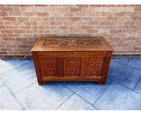 A CONTINENTAL OAK COFFER WITH TRIPLE PANEL FRONT  allover carved decoration, 108cm wide 52cm deep 62cm high