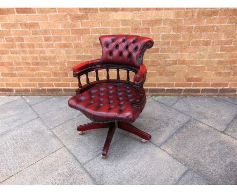 A RED LEATHER BUTTON UPHOLSTERED SWIVEL CHAIR  on five prong wooden base