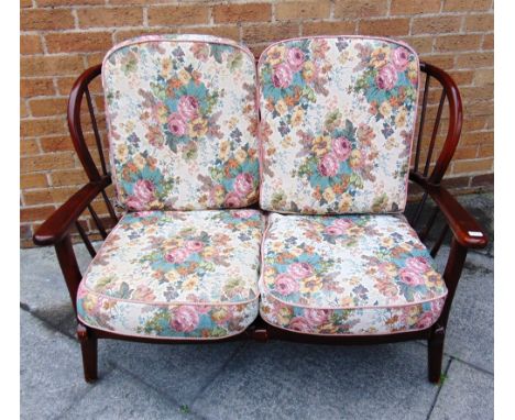 AN ERCOL STICKBACK TWO SEATER SOFA  with floral covered cushions