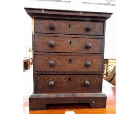 19th century oak miniature chest of drawers with moulded edge top, four drawers with turned wooden handles, raised on bracket