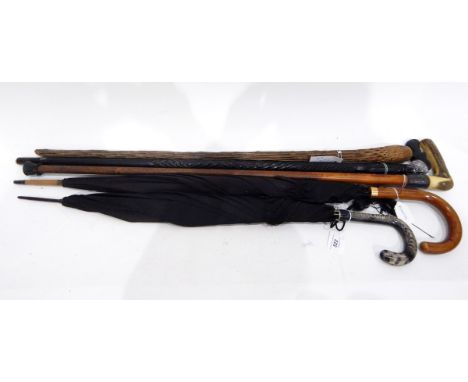 Two vintage umbrellas, a walking stick with a silver coloured metal collar, horn handle, a carved ebonised walking stick the 