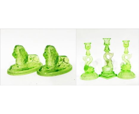 Pair of John Derbyshire green pressed glass lion ornaments, the recumbent lions on oval bases, with registration mark, 12cm h