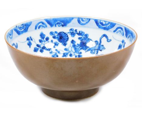 A Chinese Kangxi style blue and white bowl, the interior decorated with flowers, with an outer brown glaze on circular foot, 