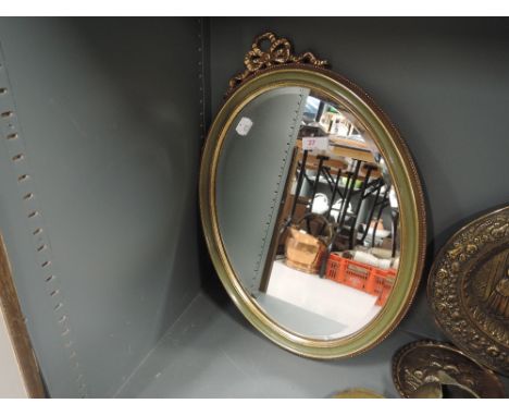 A vintage oval mirror with bevel edged glass and plaster gilt effect frame