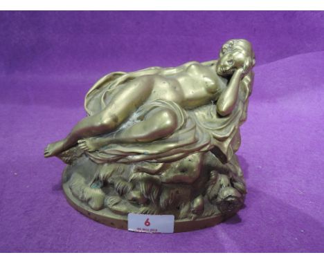 A vintage female nude study cast in bass lying atop rocky outcrop