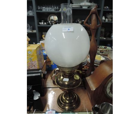 A vintage oil burning lamp with milk glass shade