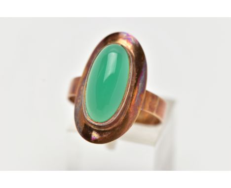 A YELLOW METAL MID 20TH CENTURY 1970s DYED CHALCEDONY RING, set with an oval dyed green Chalcedony, bezel set, within a plain