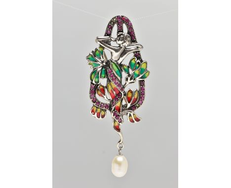 A WHITE METAL PLIQUE A JOUR BROOCH, art Noveau style, displaying a lady within flowers, set within a circular cut ruby surrou
