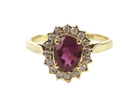A modern ruby and diamond cluster ring, in yellow metal mount, probably 14ct gold, with a central oval red stone surrounded b