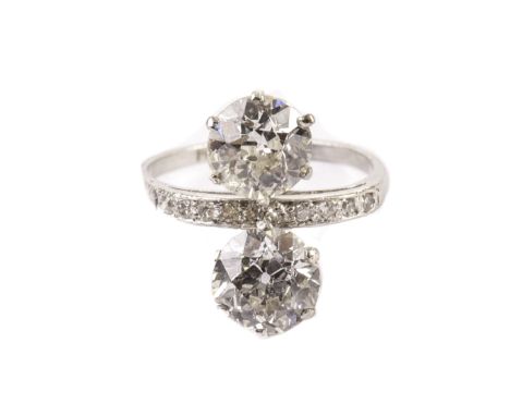 An impressive Art Deco period two stone diamond ring, the platinum ring mount set with a row of small brilliant cuts and havi