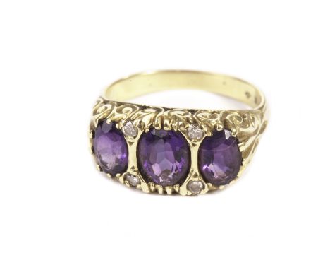 An 18ct gold and amethyst dress ring, the scroll work tablet set with three large oval purple stones and four small eight cut