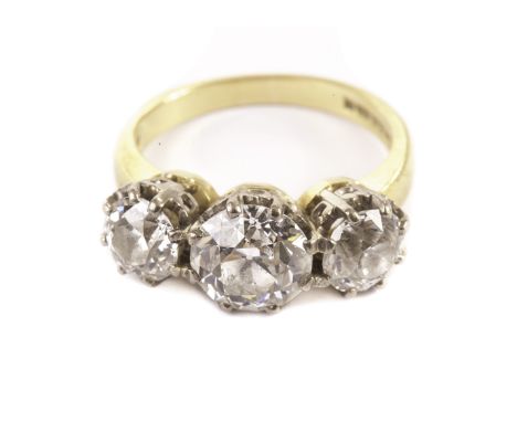 An impressive three stone diamond engagement ring, the old cuts in white metal claws on an 18ct gold band, the central stone 