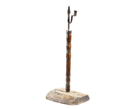 An 18th century wrought iron rushnip and candle holder, mounted on an elm bobbin and ring turned stem, with a rustic wood bas