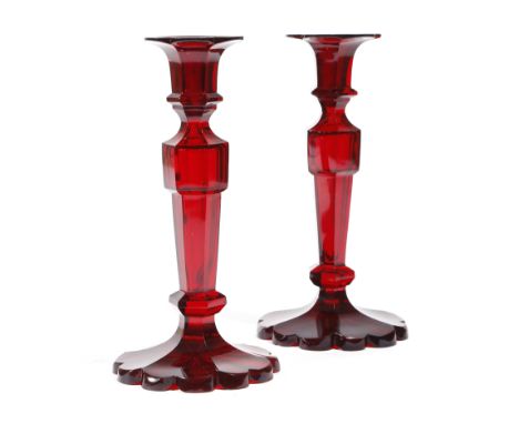 A pair of late 19th century Bohemian ruby glass candlesticks, with petal shaped sconces and faceted stems, 21cm high. (2)