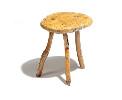 A 19th century primitive ash dairy stool, the burr seat on rustic tripod legs, 40.2cm high, 33cm wide. Provenance: The estate