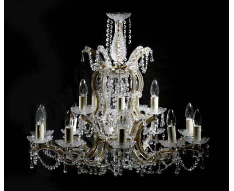 A glass and gilt brass sixteen-light chandelier, of open scroll form, with a part baluster stem and hung with drops and pear 
