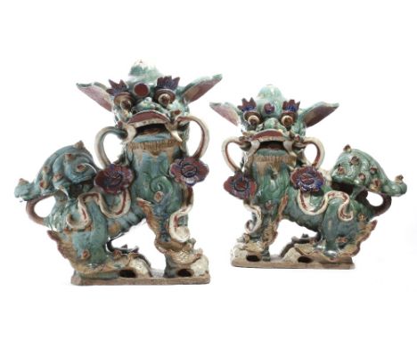 A pair of 19th century Chinese pottery models of Buddhist lion dogs, with a turquoise glaze, with a ribbon tied with flowers 
