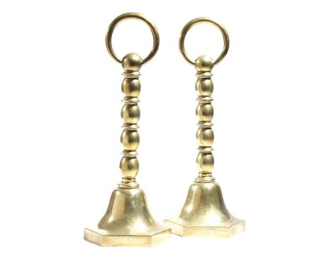 A pair of Victorian brass doorstops, each with a solid ring handle above a bobbin and disc turned hollow stem, with a bell sh